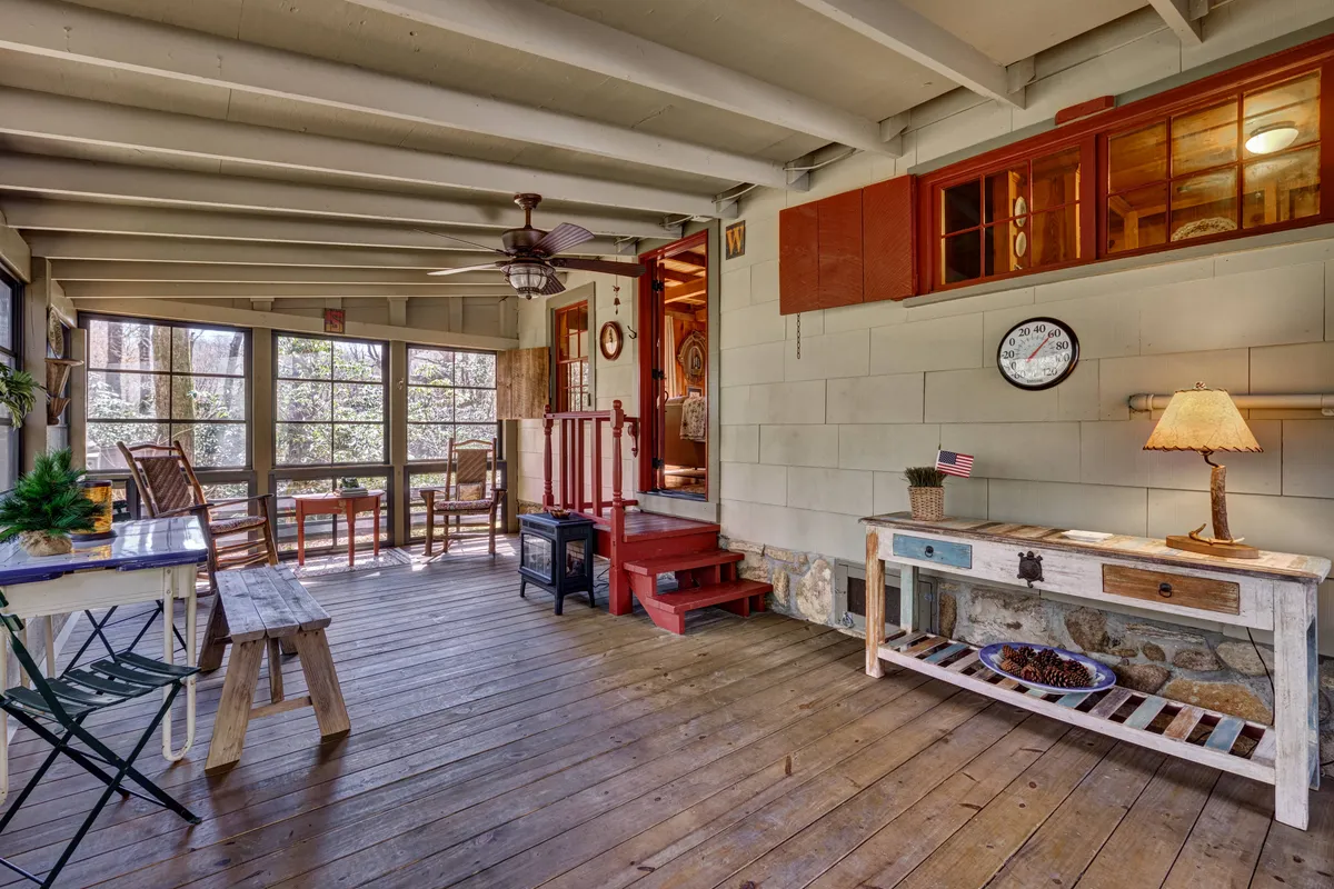 A cozy dining area with a wooden table, rocking chairs, and a decorative lamp is shown, with steps leading outside. The scene feels intimate and flexible—perfect for anything from morning coffee to romantic dinners or casual gatherings.